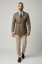 Man wearing brown double-breasted herringbone suit with tailored fit and navy tie.